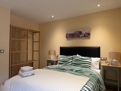 Habitación en Complejo Turístico Rural CaleaCabo con cabecero negro, ropa de cama a rayas verdes, mesillas de madera y montaña