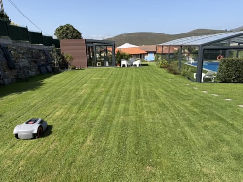 Cortacésped robótico en jardín impecable del Complejo Turístico Rural CaleaCabo, Asturias, con montañas y diseño moderno