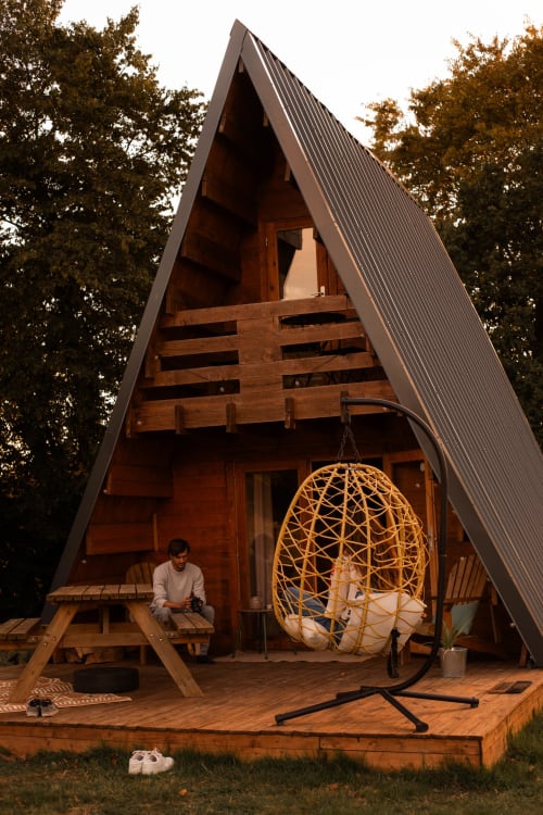 Cottage moderne en A avec toit métallique à Mesnil & Une Nuit, terrasse en bois, chaise oeuf suspendue et jardin