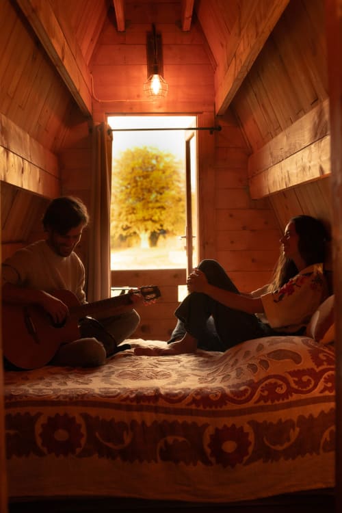 Famille profitant d'un moment convivial dans le chalet A-frame en bois de Mesnil & Une Nuit avec vue sur le jardin par les portes ouvertes