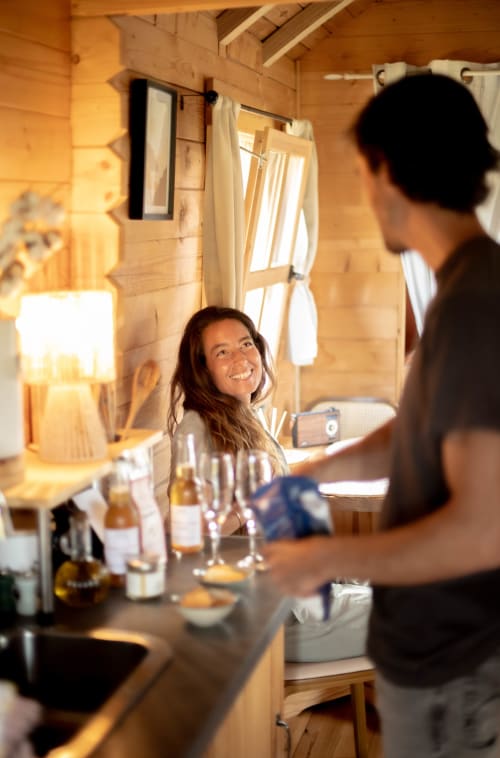 Couple savourant un verre de vin dans le cottage en bois chaleureux de Mesnil & Une Nuit B&B avec vue sur le jardin et intérieur rustique
