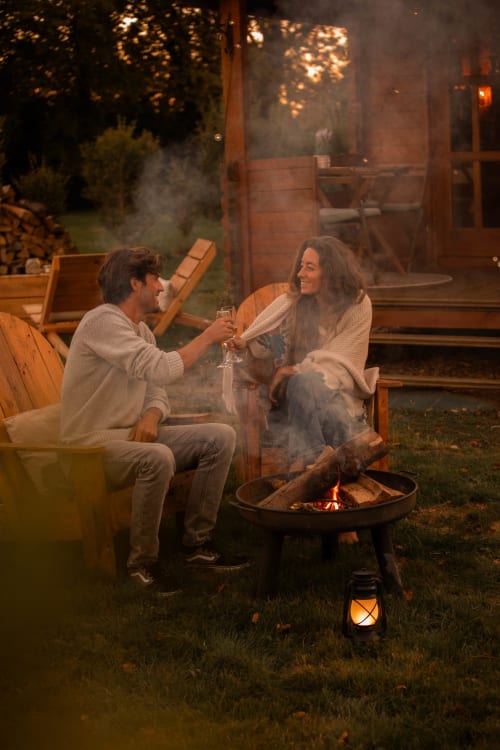 Couple levant leurs verres au coin du feu au gîte Mesnil & Une Nuit en France, ambiance soirée dans le jardin