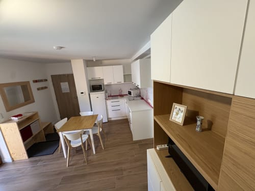 Cuisine et salle à manger modernes d'un appartement 3 chambres à GNM Vars, avec cabinetry blanc et accents en bois