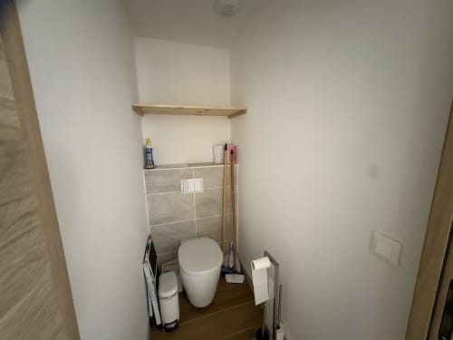 Salle de bain moderne de l'appartement Vars avec étagère en bois, dosseret carrelé et accessoires de salle de bain