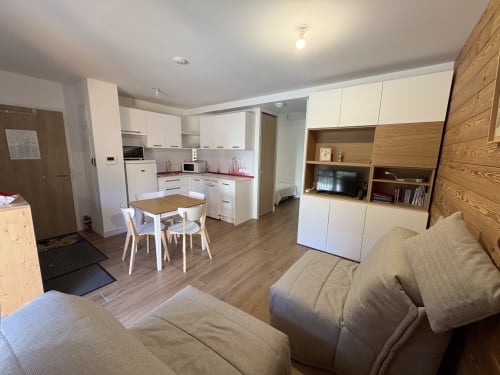 Studio moderne à Vars avec cuisine ouverte, salle à manger, séjour avec canapé et rangement bois.