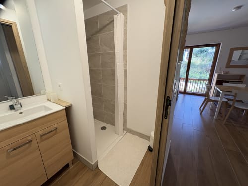Salle de bain moderne avec douche à l'italienne, meuble-lavabo en bois et parquet à l'appartement GNM à Vars