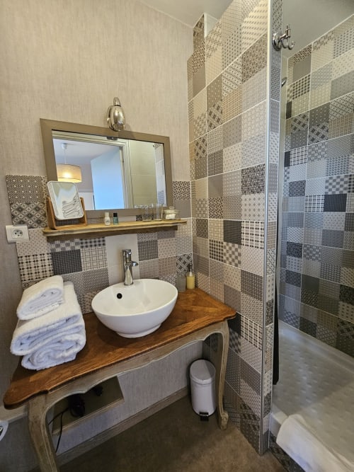 Salle de bain élégante aux Portes du Hable à Cayeux-sur-Mer : carrelage à motifs, vasque ronde blanche, meuble en bois