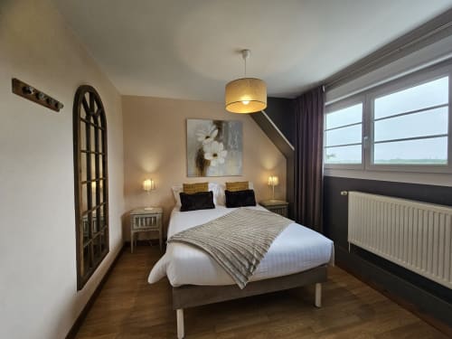Chambre moderne aux Portes du Hable à Cayeux-sur-Mer avec lit, luminaires suspendus et vue sur le jardin