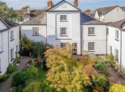 2 Doves Holiday Property cottage in Exeter with lush garden view, white walls, and enclosed outdoor space