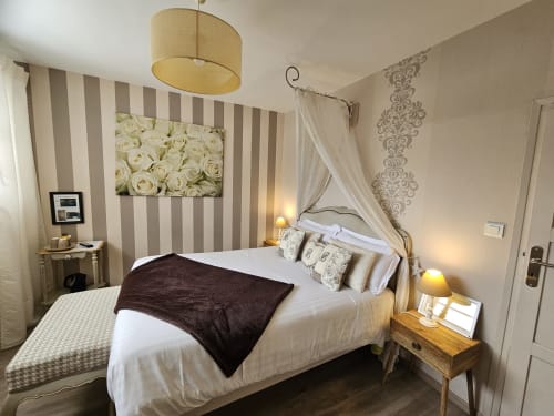 Chambre élégante des Portes du Hable avec lit à baldaquin, mur rayé et tableau de roses blanches