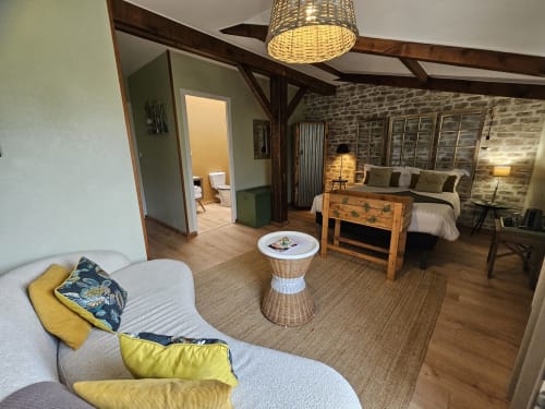 Suite moderne aux Portes du Hable avec mobilier en rotin, mur en pierre, poutres apparentes et décor contemporain