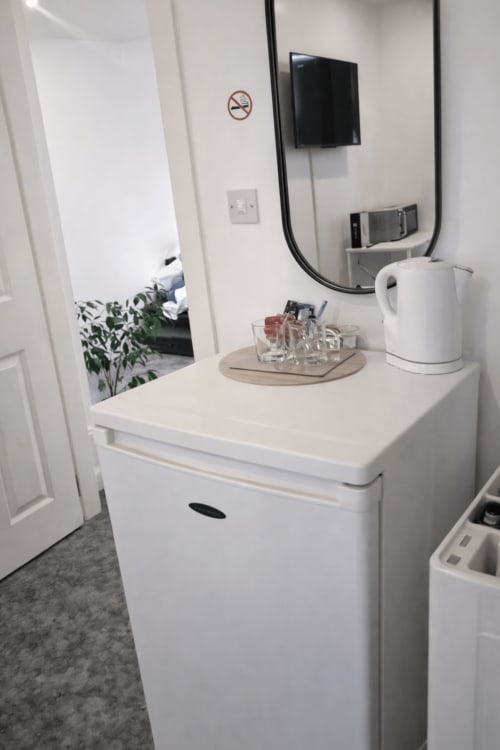 Modern hotel room vanity with mirror, kettle, and amenities at La Rose Serenity Residence in London