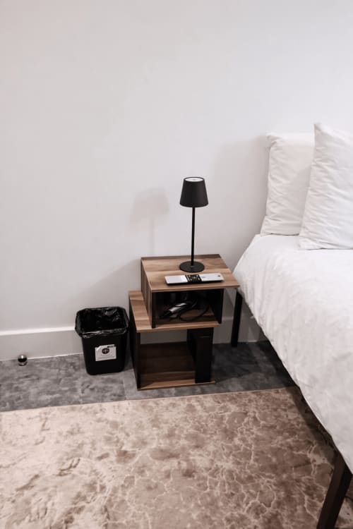 Modern bedroom at La Rose Serenity Residence with white bed, wooden nightstand, black desk lamp, and grey rug in London.