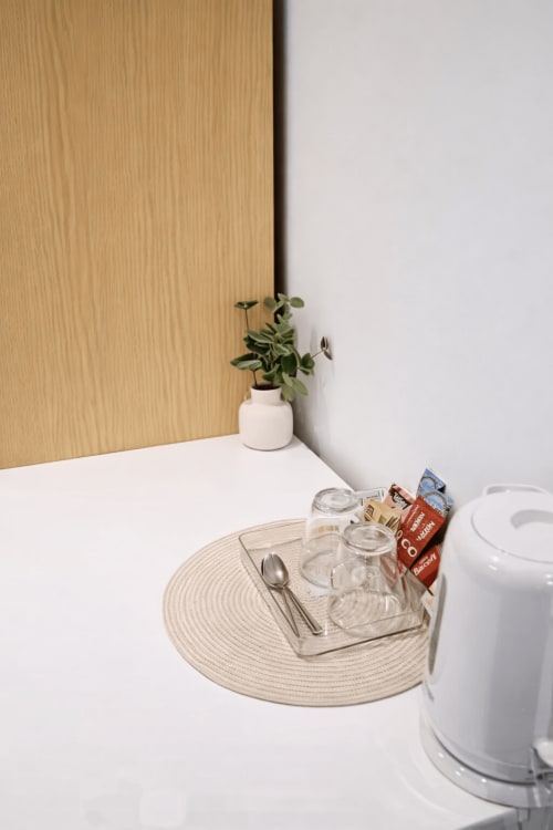 Minimalist room setting at La Rose Serenity Residence London with place setting, potted plant, and white table lamp