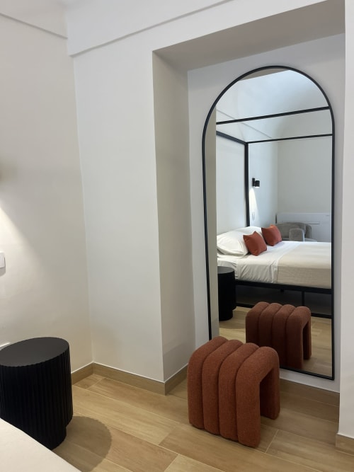 Camera moderna presso Marelia Suites con specchio arcuato, pouf rossi e letto a baldacchino con vista sulla città in appartamento italiano