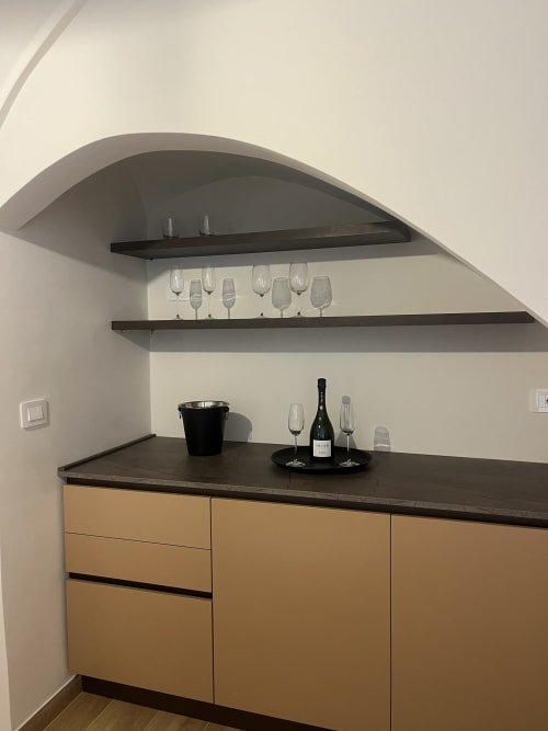 Elegante angolo bar a vini presso Marelia Suites con ripiani scuri, mobili in legno e esposizione di bottiglie in appartamento italiano