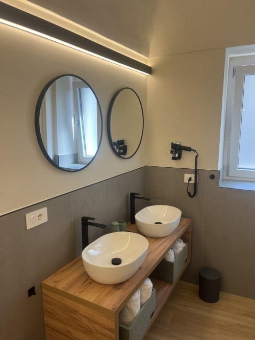 Vanity doppia moderna con specchi rotondi e rubinetteria nera nel bagno di Marelia Suites