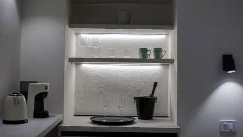Moderno angolo cottura con scaffali illuminati a LED, bicchieri, caffettiera e minibar presso Marelia Suites in Italia