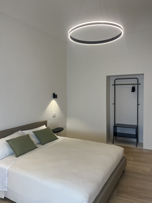 Camera moderna di Marelia Suites con lampada LED ovale, cuscini verdi e appendiabiti in appartamento italiano