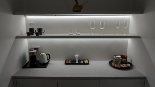 Angolo cucina moderno presso Marelia Suites con macchina da caffè, bollitore bianco, bicchieri e servizi su bancone grigio con illuminazione LED