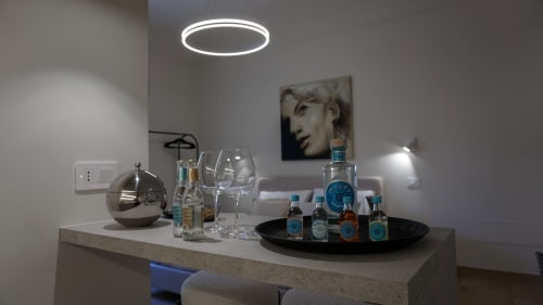 Minibar dell'aparthotel Marelia Suites con alcolici, bicchieri e luce neon a soffitto nella camera d'hotel italiana