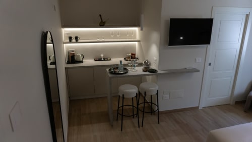 Angolo cottura moderno presso Marelia Suites con bancone bar, ripiani illuminati, TV e pavimenti in legno