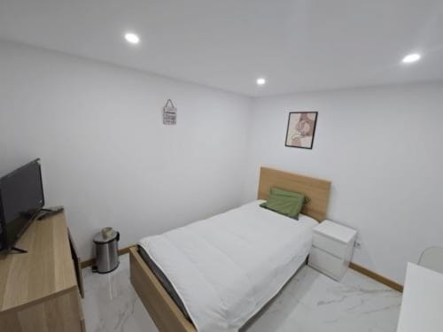 Quarto moderno no Hotel Boeing AL em Moreirada Maia com cama, TV e almofada de destaque verde