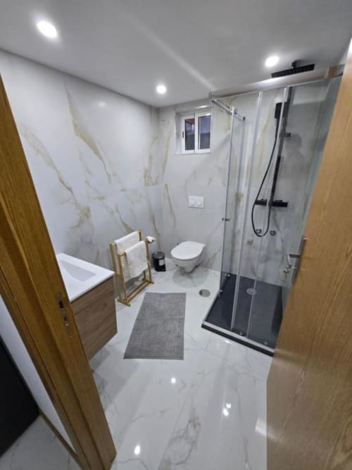 Casa de banho moderna do hotel Boeing AL em Moreirada Maia com paredes de mármore, duche tipo walk-in, sanita e toalheiro aquecido