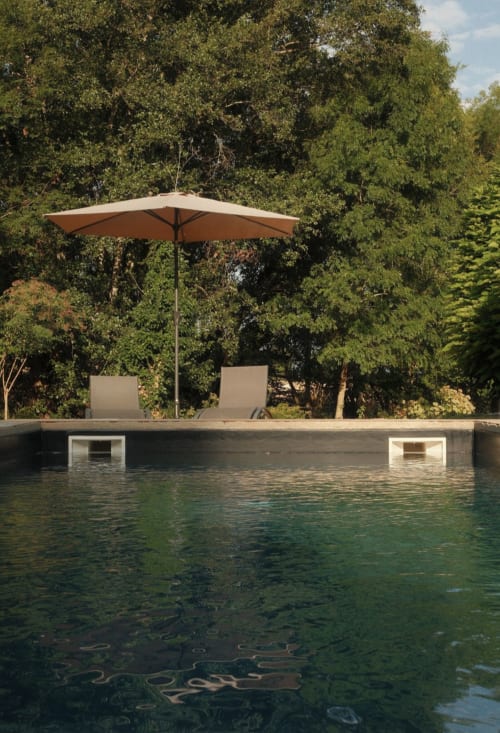Piscine du Moulin Renaudiots avec parasol beige et chaises longues face aux jardins verdoyants d'Autun