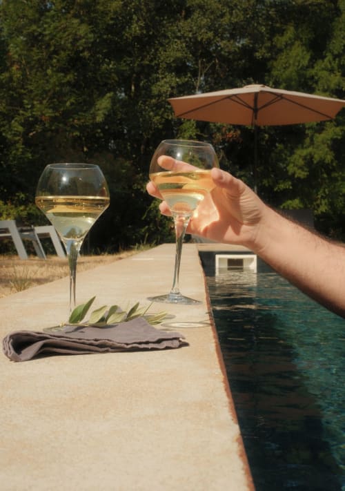 Main tenant un verre de vin blanc près de la piscine au Moulin Renaudiots à Autun, France