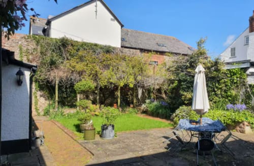 Clara Place cottage garden at 2 Doves, Exeter featuring dining area, lawn and climbing ivy-covered walls
