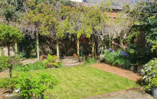 Private fenced garden at 2 Doves Holiday Property in Exeter with lush lawn, mature trees, and outdoor seating area