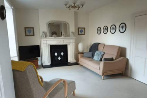 Elegant Clara Place cottage sitting room at 2 Doves Holiday Property, Exeter, with fireplace, comfortable seating, and garden