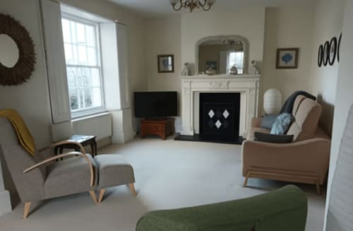 Elegant sitting room at Clara Place cottage in Exeter with fireplace, comfortable seating, TV, and garden views