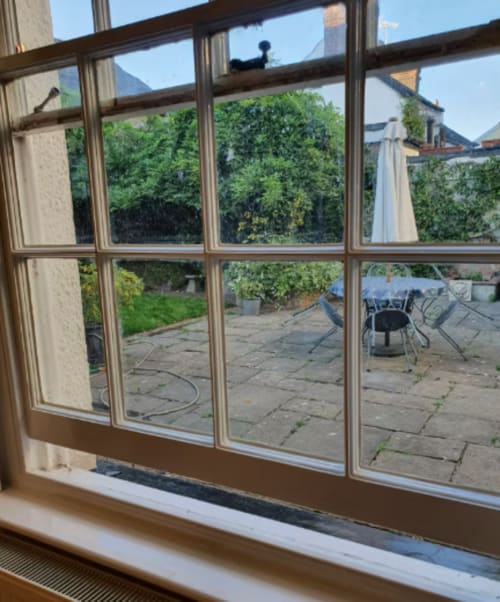 View from cottage window overlooking private garden with patio seating at 2 Doves Holiday Property, Exeter