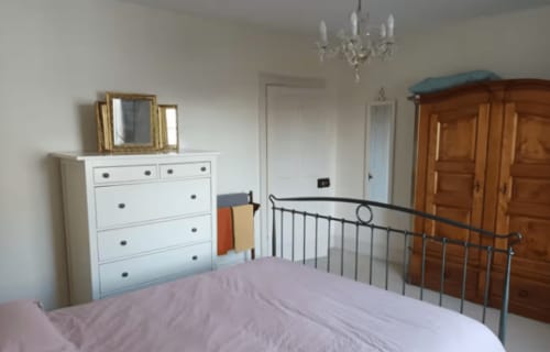 Bedroom at Clara Place cottage in Exeter with metal bed frame, white chest of drawers, wooden wardrobe, and crystal