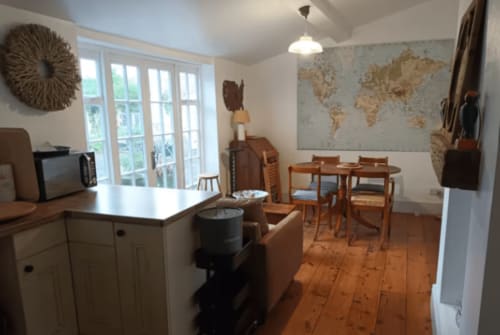 Clara Place cottage at 2 Doves, Exeter - open-plan kitchen and dining area with wooden table, garden view windows, and world