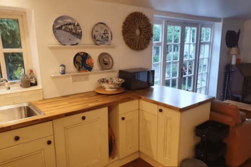 Clara Place cottage kitchen with cream cabinetry, wooden counters, and decorative plates at 2 Doves Holiday Property, Exeter