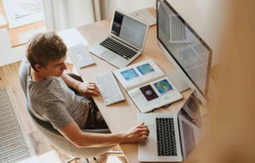 Huésped trabajando en escritorio con laptops y materiales de diseño en el Hostal Zaragoza Centro