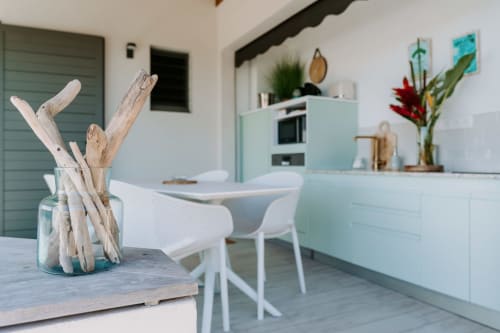 Modern kitchen-dining area at Le Malanga apartment in Sainte-Anne with driftwood decor, white chairs, and light blue