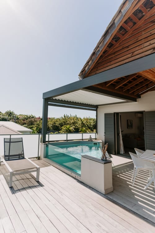 Private pool terrace at Habitation I'SEO in Sainte-Anne, Guadeloupe, featuring turquoise pool, wooden deck, lounge chairs,