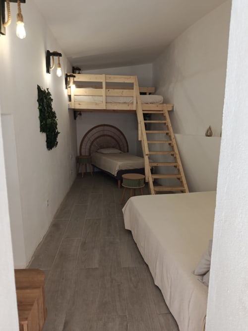 Quarto compacto na pousada Cerro da Janela com cama alta, cama de solteiro, escada de madeira e iluminação pendente