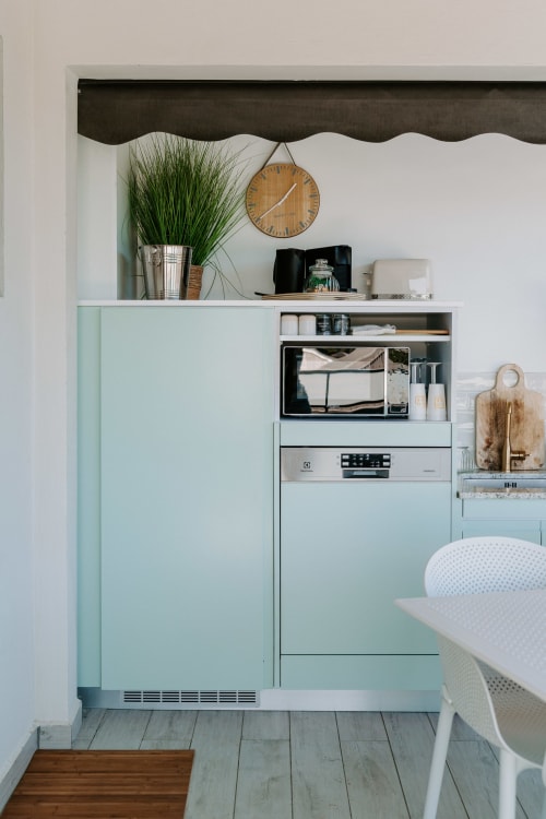Kitchenette moderne à Habitation l'SEO avec mobilier menthe, micro-ondes, lave-vaisselle et finitions bois à Sainte-Anne