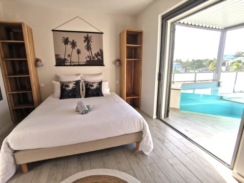 Chambre moderne à Habitation I'SEO avec vue sur la piscine, décoration de palmiers, étagères en bois et accès direct à la terrasse privée