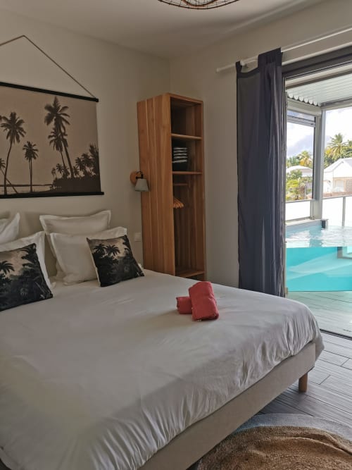 Chambre Le Voyageur à Habitation I'SEO avec vue sur la piscine, art botanique, rangements en bois et piscine privée turquoise