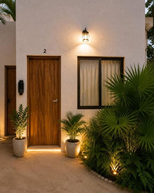 Entrada de la Suite 02 en Hotel Holbox Centro con puerta de madera, plantas iluminadas y patio moderno en Holbox