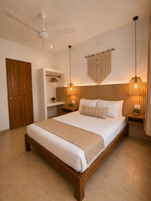 Habitación moderna del Hotel Holbox Centro con cama de madera, ropa de cama blanca, luces colgantes y decoración mural de macramé