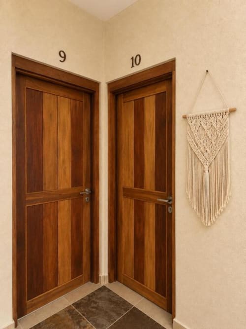 Entrada de suite del Hotel Holbox Centro con puertas de madera, paredes beige y tapiz de macramé en Holbox, México