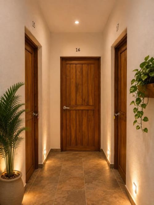 Pasillo moderno del Hotel Holbox Centro con puertas de madera, iluminación cálida y plantas en macetas en Holbox, México