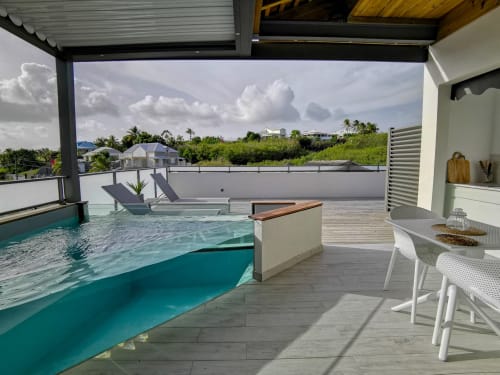 L'appartement Le Voyageur à l'Habitation I'SEO à Sainte-Anne dispose d'une terrasse privée avec piscine aux eaux turquoise et transats,